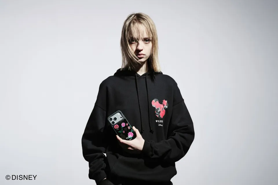 CASETiFY × WILDSIDE × Disney campaign — model in a black hoodie holding the red Mickey rose case