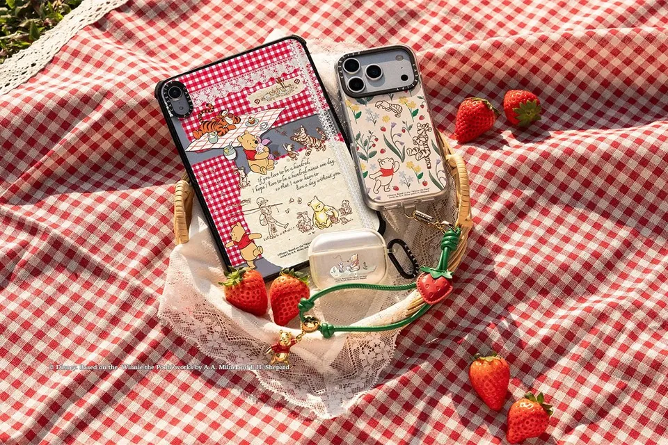 Storybook Pooh cases on a gingham picnic blanket with strawberries
