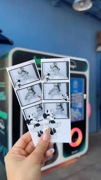 Two Minnie Mouse photo strips held up in front of a Disney photo booth
