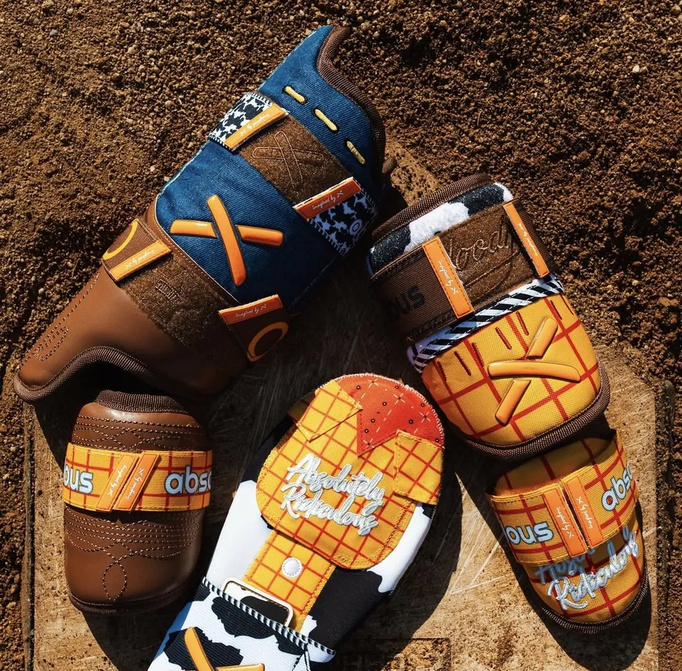 Absolutely Ridiculous × Toy Story gear — Woody plaid, cow print and boot-leather guards laid out on home plate
