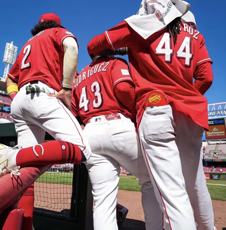 Cincinnati Reds players at the dugout rail wearing Lightning McQueen gear